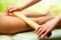 Hands massaging female legs with bamboo.