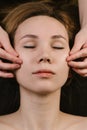 Hands massaging woman`s cheeks with fingers at asian beauty clinic. Top view