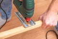 The hands of a master carpenter with an electric jigsaw in his hands cutting off a piece of wood. Male hands using fret Royalty Free Stock Photo