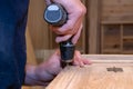 hands of a master carpenter install the hinges on the cabinet with a hand-held power tool screwdriver. Production of handmade