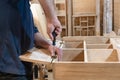 hands of a master carpenter install the hinges on the cabinet with a screwdriver. Production of handmade