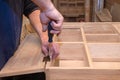 hands of a master carpenter install the hinges on the cabinet with a screwdriver. Production of handmade wooden furniture.