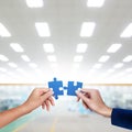 Hands matching blue jigsaw of teamwork conceptual at factory background