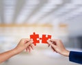 Hands matching red jigsaw of teamwork conceptual at factory background