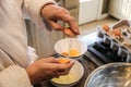 Hands of mature woman in bathrobe separating eggs on island in kitchen - Selective focus Royalty Free Stock Photo