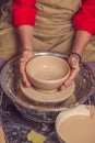 Hands of mature woman master of ceramics working on a potter& x27;s wheel, making plate of clay in art studio. Royalty Free Stock Photo