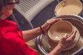 Hands of mature woman master of ceramics working on a potter& x27;s wheel, making plate of clay in art studio. Royalty Free Stock Photo