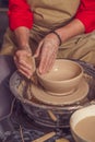 Hands of mature woman master of ceramics working on a potter's wheel, making plate of clay in art studio. Royalty Free Stock Photo