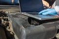 Hands of a mechanic with gloves doing a check up of a car`s diesel engine with tools and wrenches and laptop