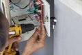 Hands of a mechanic holding a automatic screwdriver to fix the vending machine.