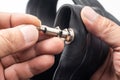 Hands of the mechanic Release the air from the motorcycle tire and remove the valve-stem needle by unscrewing it from the stem.