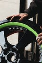 Hands of a mechanic on top of a wheel of a green super sports car. Royalty Free Stock Photo