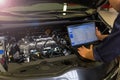 Mechanic Using Laptop While Examining Car Engine