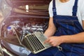 Mechanic Using Laptop While Examining Car Engine