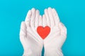 Hands in medical gloves holding a red heart shape