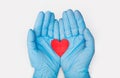 Hands in medical gloves holding a red heart shape