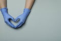 Hands in medical gloves shows heart on light gray background Royalty Free Stock Photo