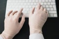 Hands in medical protection gloves typing on laptop keyboard, virus epidemy concept