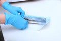 The hands of a medical worker in blue gloves pack dental devices for sterilization. Unrecognizable photo.