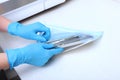 The hands of a medical worker in blue gloves pack dental devices for sterilization. Unrecognizable photo. Only hand.