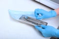 The hands of a medical worker in blue gloves are Packed in a craft package of dental devices for sterilization
