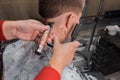 The hands of a man of an experienced hairdresser hold a brush for hair removal and cut the back of the head, make a haircut for a Royalty Free Stock Photo