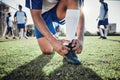 Hands, man and tie shoes on soccer field, prepare for training or fitness games. Closeup, football player or athlete