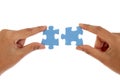 Hands merging two jigsaw puzzle pieces against white