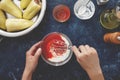 Hands mixing tomato sauce and sour cream in glass bowl for making filled paprika.