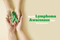 Hands of mother and child hold green ribbon - symbol of fight against disease. World lymphoma awareness day. September