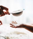 Hands of mother and child sieving flour