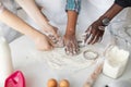 Hands of multiracial family with child squeezing out the dough using cookie cutters