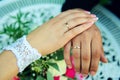 Hands of newlyweds on the background of wedding bouquet. Gold wedding rings on the finger of bride and groom, close-up. Concept Royalty Free Stock Photo