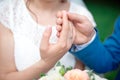 Hands of the newlyweds bride and groom with gold wedding rings close-up on a background of a wedding bouquet of roses Royalty Free Stock Photo