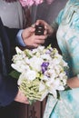 The hands of the newlyweds hold a box-case with gold wedding rings and a bouquet of flowers. A bouquet of white cream roses and Royalty Free Stock Photo