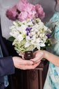 The hands of the newlyweds hold a box-case with gold wedding rings and a bouquet of flowers. A bouquet of white cream roses and Royalty Free Stock Photo