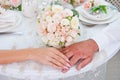 Hands of newlyweds with rings on the fingers lying on the table on the background of the wedding bouquet Royalty Free Stock Photo