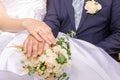 The groom`s hands with wedding rings lie on top of each other, on the bride`s bouquet of roses Royalty Free Stock Photo