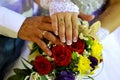 Hands of the newlyweds with wedding rings on the background of the wedding bouquet Royalty Free Stock Photo