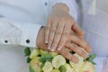 Hands of the newlyweds with wedding rings on the wedding bouquet. Hands of the bride and groom on a bouquet of flowers Royalty Free Stock Photo