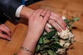 Hands of the newlyweds with wedding rings on the wedding bouquet. Hands of the bride and groom on a bouquet of flowers Royalty Free Stock Photo