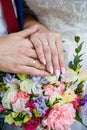 Hands of newlyweds with wedding rings and a bouquet of flowers. The groom in a blue suit and red tie. The concept of Royalty Free Stock Photo