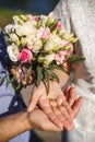 Hands of newlyweds with wedding rings lying on their palms and a wedding bouquet of flowers. Concept of wedding love and Valentine Royalty Free Stock Photo