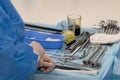 Hands of a nurse or medical assistant on a table with surgical instruments. Glasses with disinfectant solutions, scissors, clips, Royalty Free Stock Photo