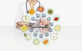 Hands of nutritionist doctor touch digital tablet at office desk with symbols fruits icons isolated on white background, healthy