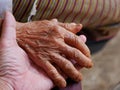 Hands of an old hard working woman on a hand of a younger man - care for elderly people Royalty Free Stock Photo