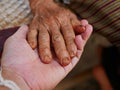 Hands of an old hard working woman on a hand of a younger man - care for elderly people Royalty Free Stock Photo