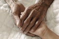 Hands of the old man and a child`s hand on the white bed in a hospital Royalty Free Stock Photo