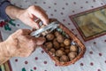 Hands of Old Man Grandpa Pensioner cracks a walnut with a metal nutcracker at a kitchen table, Germany Royalty Free Stock Photo
