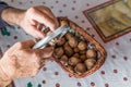 Hands of Old Man Grandpa Pensioner cracks a walnut with a metal nutcracker at a kitchen table, Germany Royalty Free Stock Photo